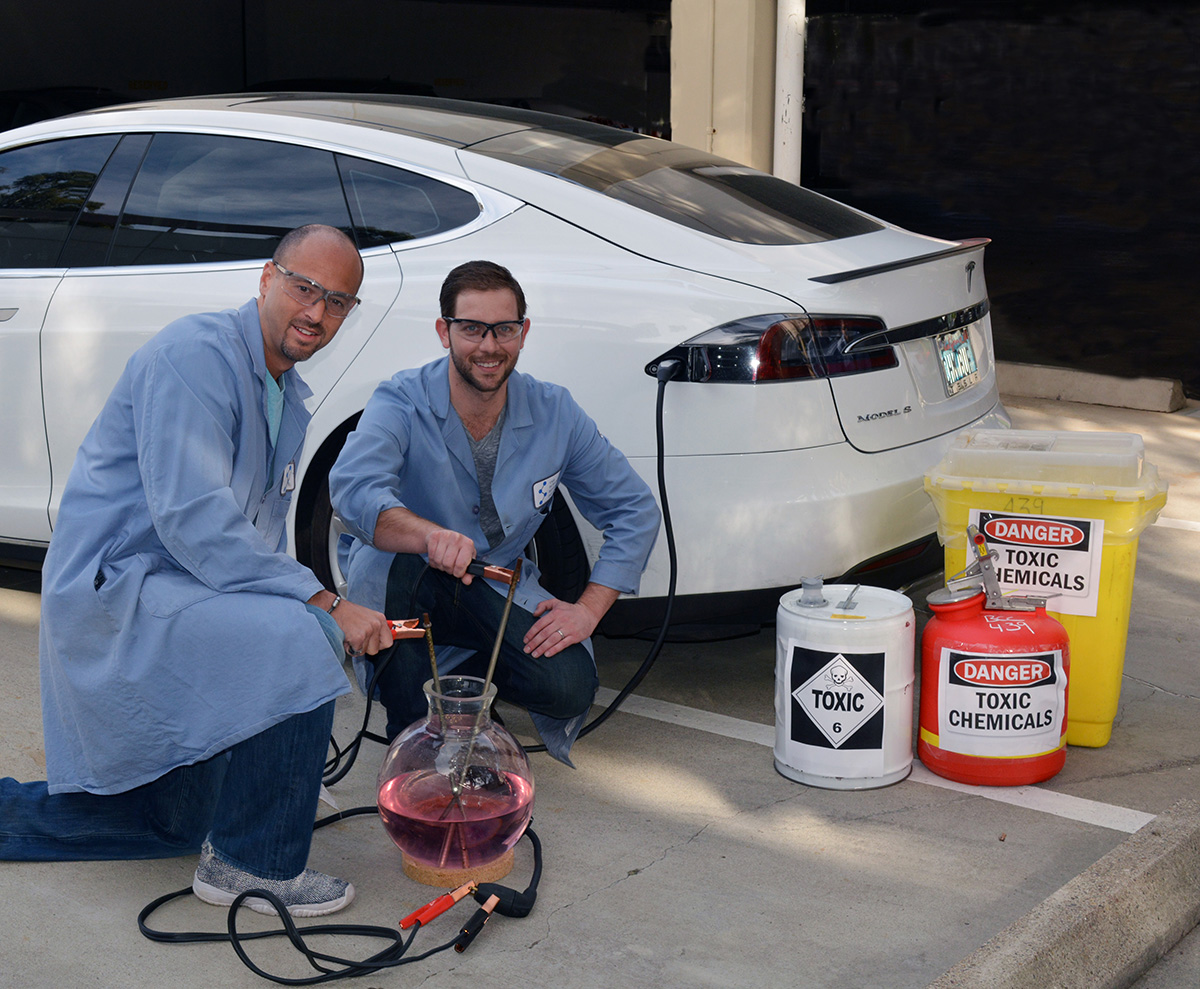 Scripps Research Institute chemists Phil Baran (left) and Evan Horn pose in front of an electric car, whose principles of sustainable transport pertain to the sustainable chemistry in the Baran lab’s new electrochemical allylic oxidation reaction, which eliminates toxic chemicals from a widely employed chemical process.